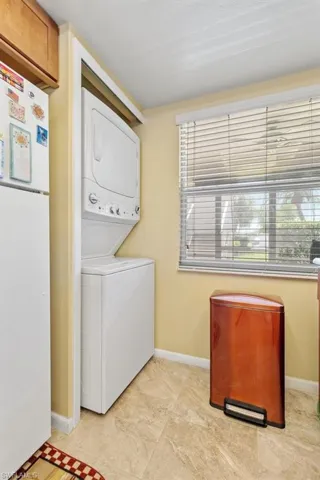 Laundry area featuring stacked washer and dryer and light tile flooring