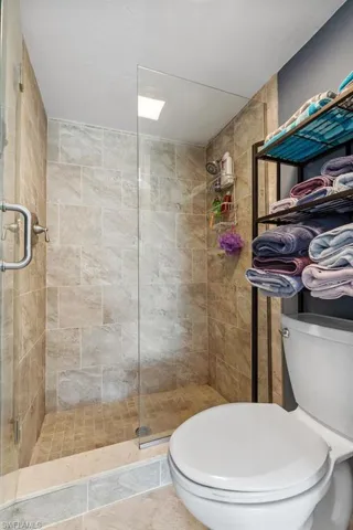 Bathroom featuring walk in shower, tile flooring, and toilet