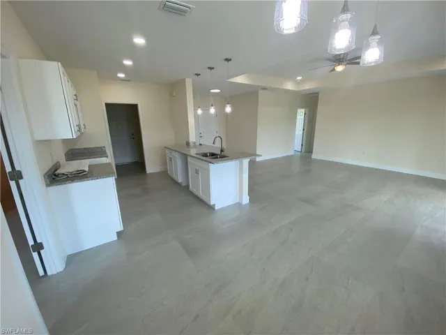 Kitchen with dark stone countertops, white cabinetry, hanging light fixtures, open floor plan, and recessed lighting