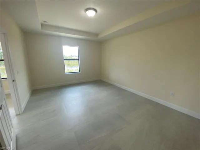 Unfurnished room with a tray ceiling and light flooring