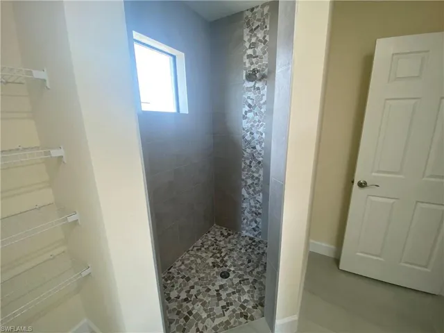 Bathroom featuring a tile shower and baseboards