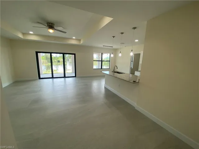 Unfurnished living room featuring recessed lighting, a raised ceiling, and ceiling fan