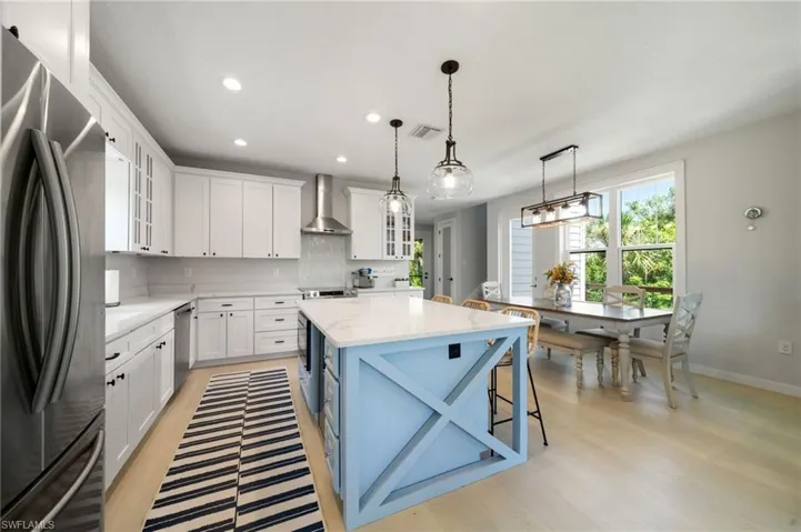 Kitchen featuring glass insert cabinets, stainless steel appliances, white cabinets, pendant lighting, and recessed lighting