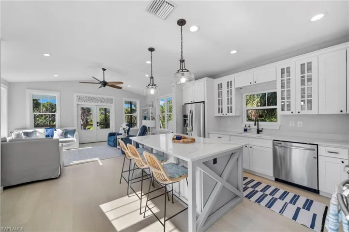 Kitchen with open floor plan, pendant lighting, healthy amount of natural light, a breakfast bar area, and lofted ceiling