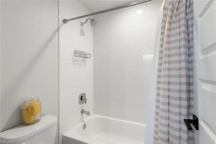 Bathroom with shower / bath combo and a textured wall