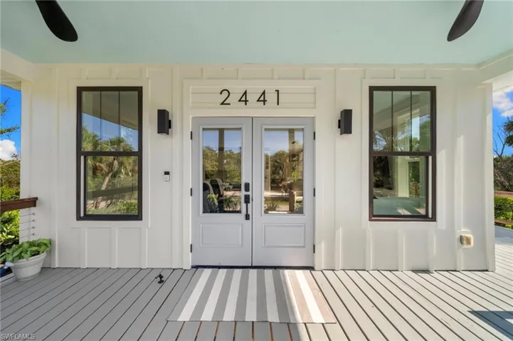Entrance to property featuring ceiling fan, a wooden deck, and board and batten siding