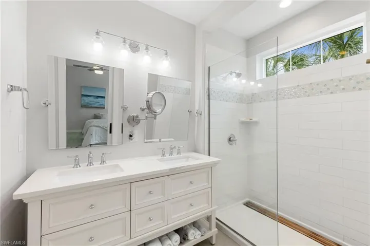 Ensuite bathroom with walk in shower, double vanity, and a ceiling fan