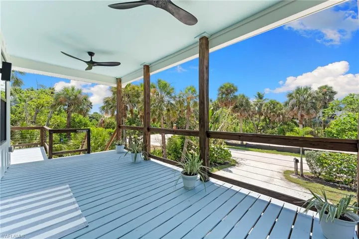 Deck featuring view of wooded area and a ceiling fan