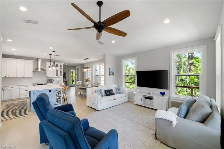 Living room featuring recessed lighting, vaulted ceiling, ceiling fan, and light wood-type flooring