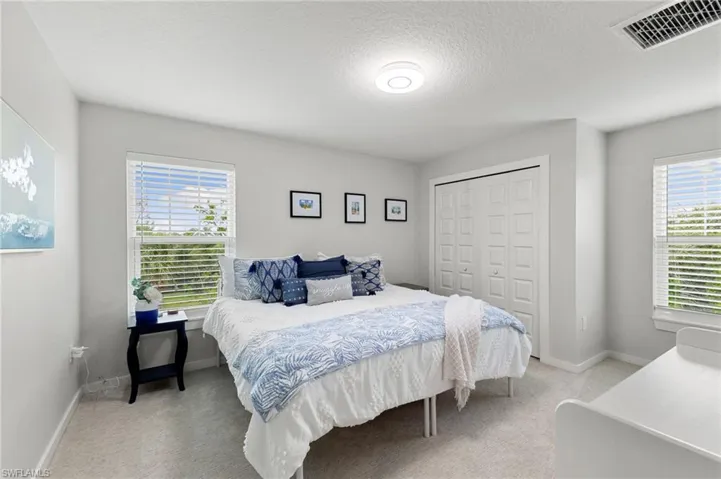 Bedroom with light colored carpet, a textured ceiling, and a closet
