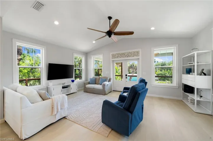 Living area featuring light wood-type flooring, french doors, a ceiling fan, lofted ceiling, and recessed lighting