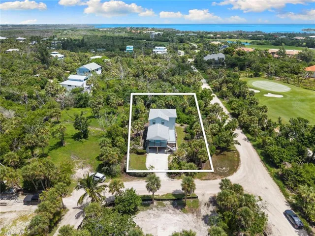 Aerial view of property's location featuring property parcel outlined, a local golf course, and a nearby body of water