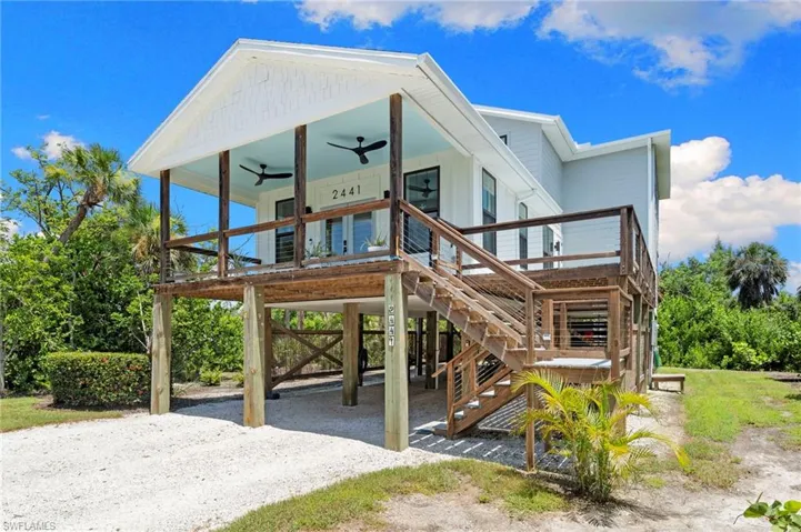 View of front facade with a carport, ceiling fan, driveway, and stairs