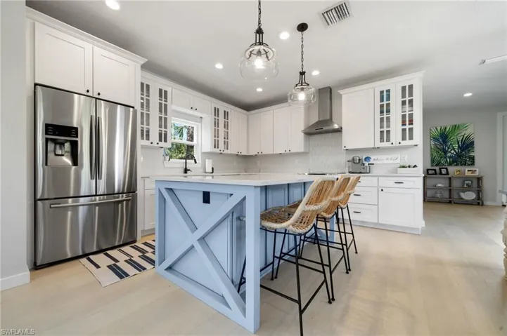 Kitchen featuring glass insert cabinets, stainless steel refrigerator with ice dispenser, white cabinets, a center island, and recessed lighting