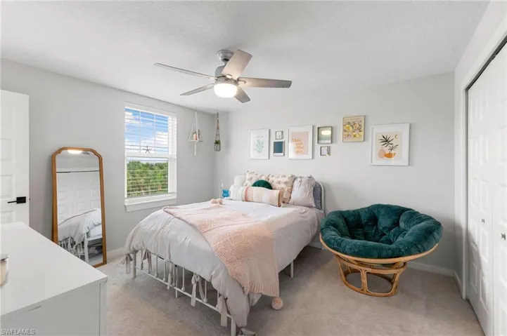 Bedroom featuring a closet, a textured ceiling, ceiling fan, and light carpet