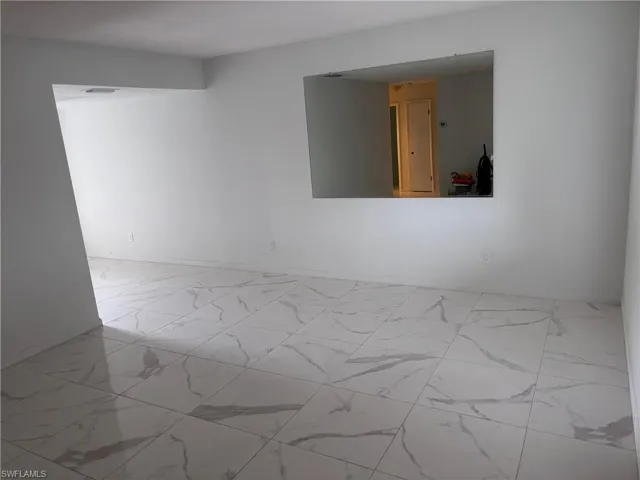 Spare room with marble look tiles and baseboards
