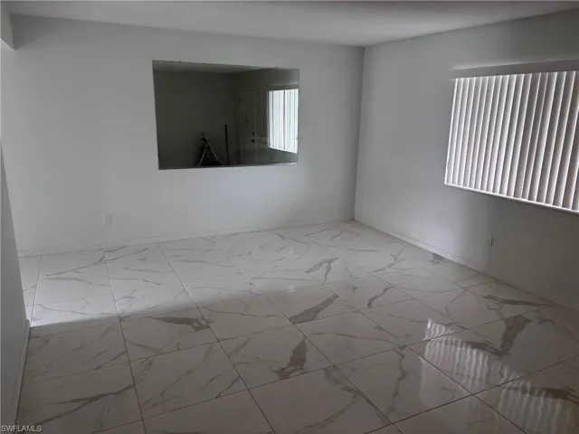 Spare room featuring marble finish floors and baseboards
