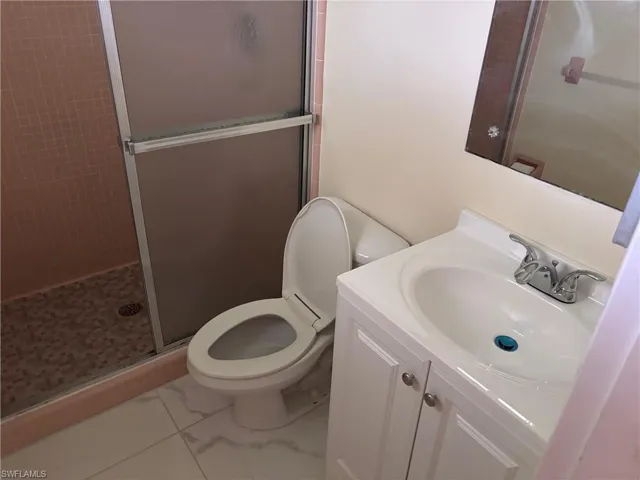 Full bathroom with a shower stall, marble finish floors, toilet, and vanity