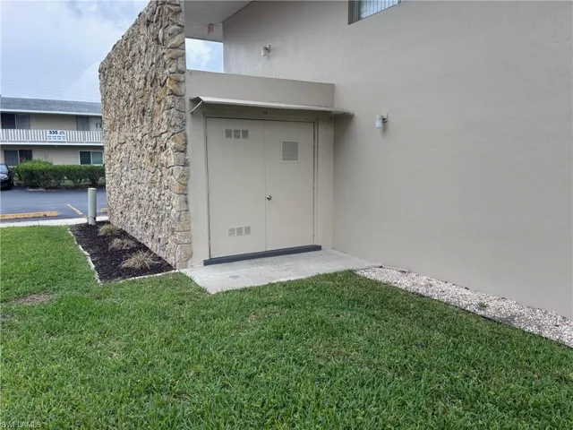 View of exterior entry with stucco siding, a lawn, and stone siding