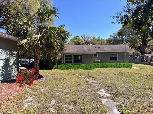 Back of house featuring a lawn, cooling unit, fence, and stucco siding