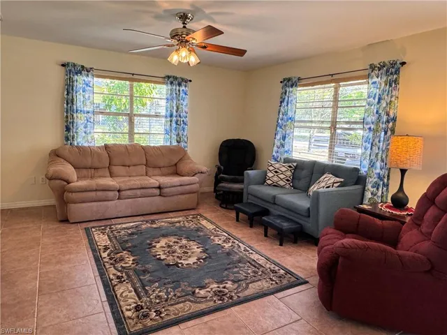 Living room featuring tile patterned flooring, baseboards, and ceiling fan