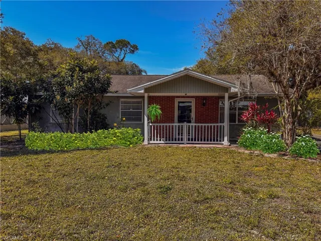 Ranch-style house featuring a front yard, covered porch, and brick siding