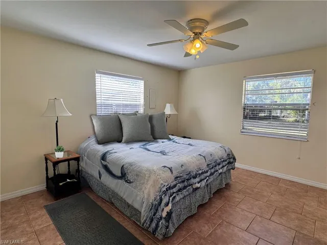 Bedroom featuring light tile patterned floors, ceiling fan, and baseboards