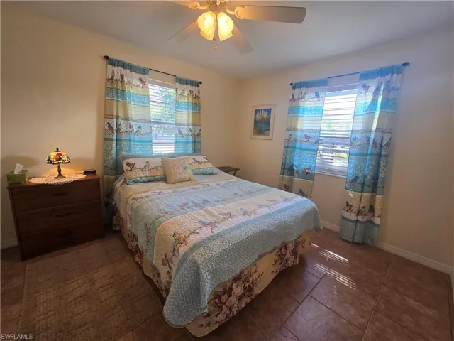 Tiled bedroom featuring a ceiling fan and baseboards