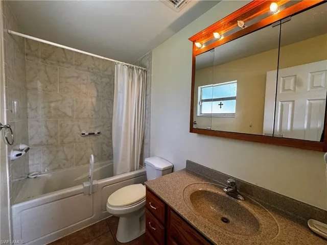 Bathroom with tile patterned flooring, toilet, visible vents, vanity, and shower / bath combo