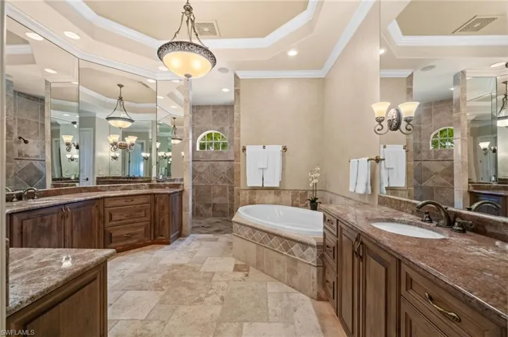 Luxurious primary bath featuring dual vanities, custom cabinetry, a soaking tub, spacious walk-in shower, and elegant architectural details.
