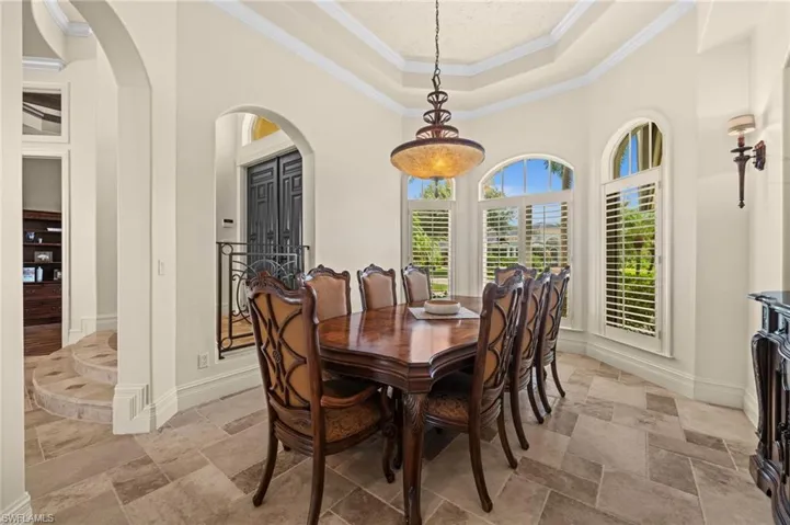 Elegant formal dining room featuring a tray ceiling, arched architectural details, and ample space for hosting family and guests.