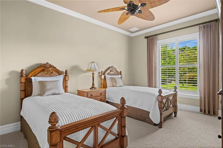 Spacious guest bedroom featuring a tray ceiling, large windows, and abundant natural light.