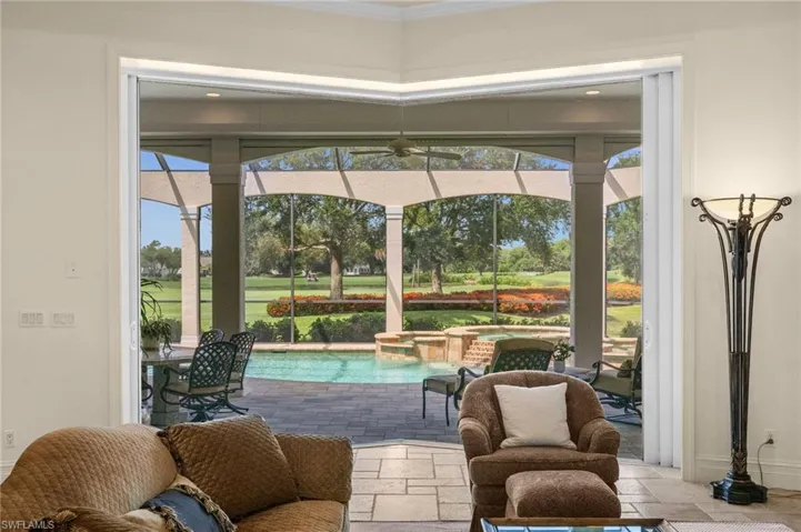 Inviting sitting area with expansive windows framing the pool, lanai, and lush outdoor views.
