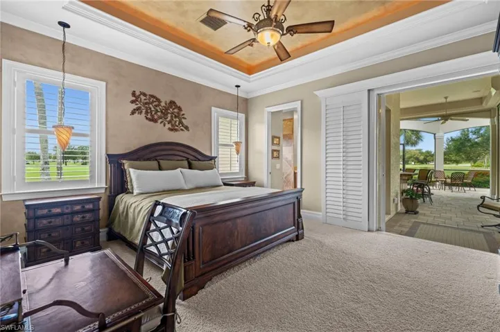Generous guest suite featuring a tray ceiling, abundant natural light, and direct access to the outdoor living area.
