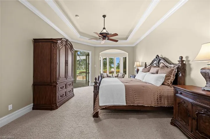 Spacious primary suite featuring a tray ceiling, private sitting area, and direct access to the outdoor living space.