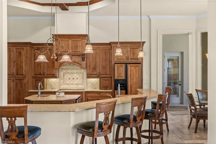 Gourmet kitchen featuring custom wood cabinetry, generous counter space, and a breakfast bar that opens to the sunlit morning room.