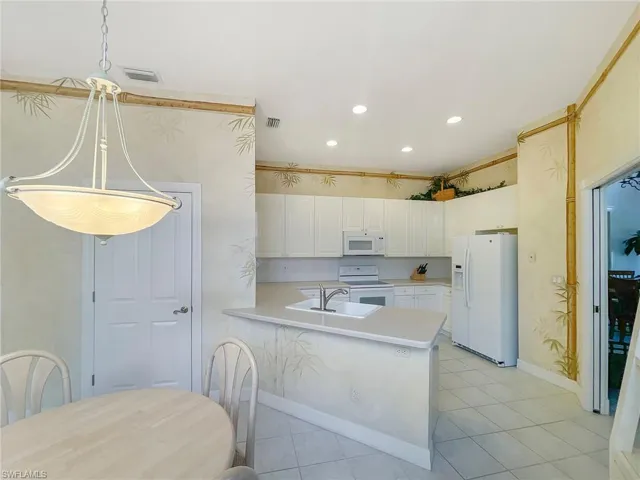 Kitchen featuring white appliances, light countertops, recessed lighting, white cabinets, and a peninsula