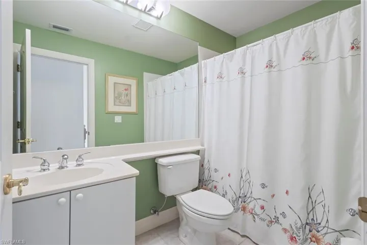 Bathroom with vanity, toilet, tile patterned floors, and curtained shower