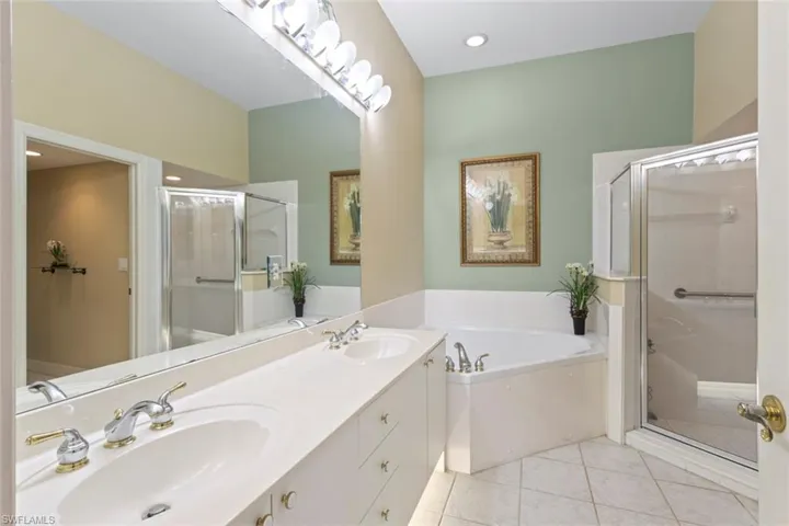 Bathroom featuring a bath, a stall shower, double vanity, and tile patterned flooring