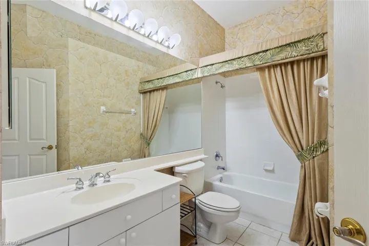 Full bath with shower / bathtub combination with curtain, toilet, vanity, and tile patterned flooring