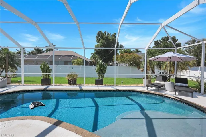 Screened pool area featuring a curved pool with a sun shelf
