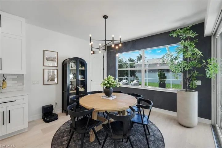Open-concept dining area featuring light wood-finish flooring and a contemporary chandelier