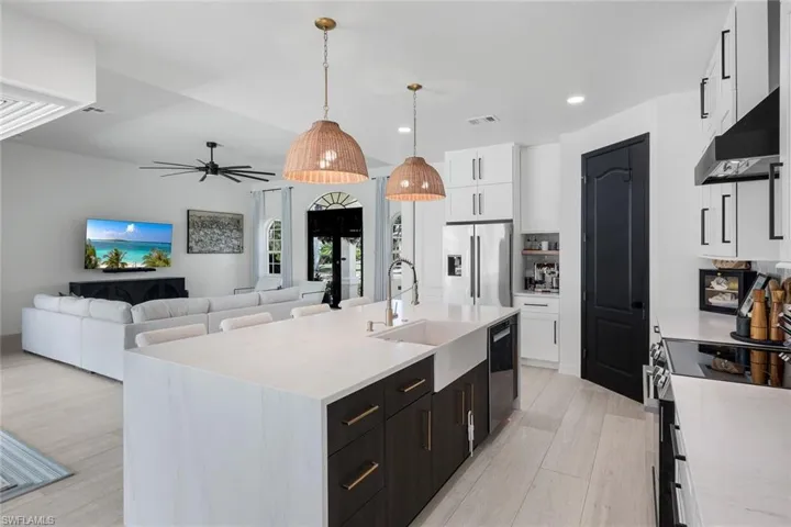 Kitchen featuring an expansive island with a farmhouse sink, stainless steel appliances, contemporary cabinetry, and light wood-finish flooring