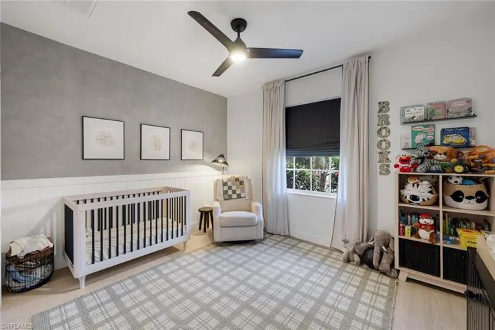 Light-filled room featuring a ceiling fan, a window with a dark roller shade, and light wood-finish flooring