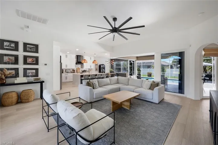 Open-concept living space with light wood-finish flooring and a contemporary multi-blade ceiling fan