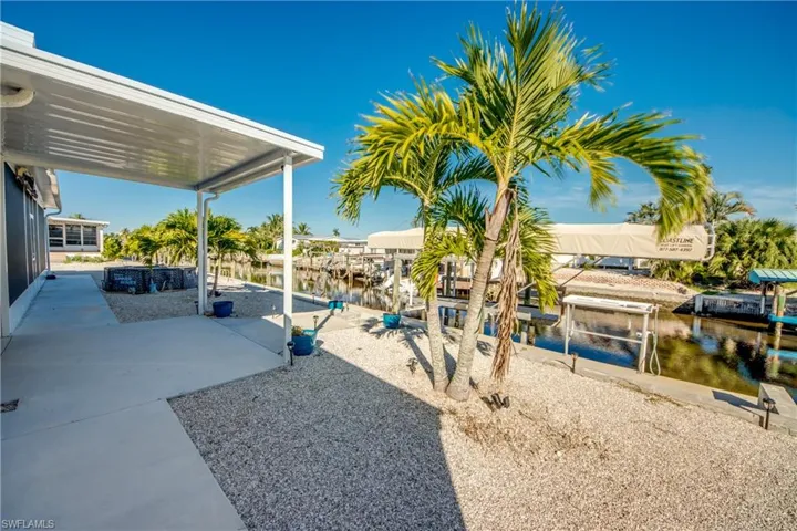 View of yard featuring boat lift, a water view, a dock, and a patio area