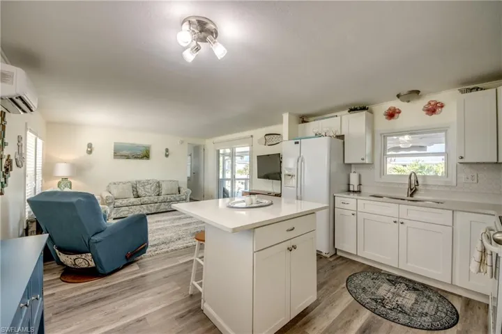 Kitchen with a breakfast bar, white cabinets, a center island, and light wood-style flooring
