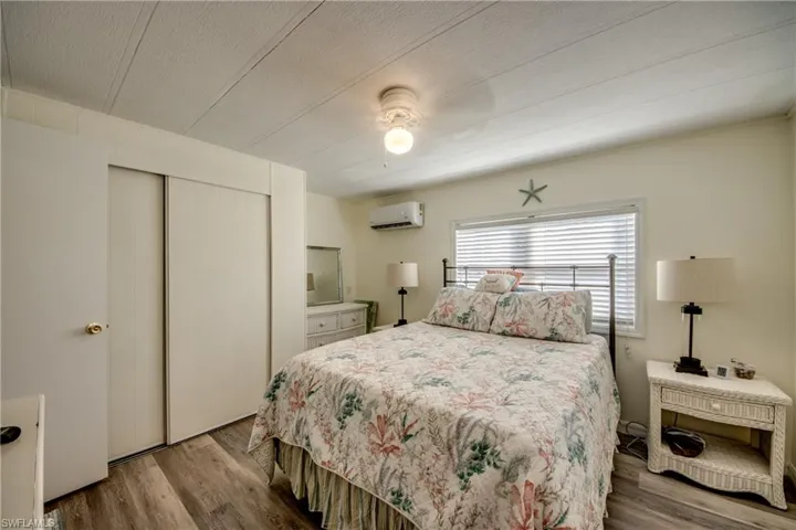 Bedroom featuring a closet, wood finished floors, ceiling fan, and a wall mounted AC