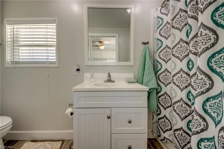 Bathroom with vanity, a shower with curtain, and a ceiling fan