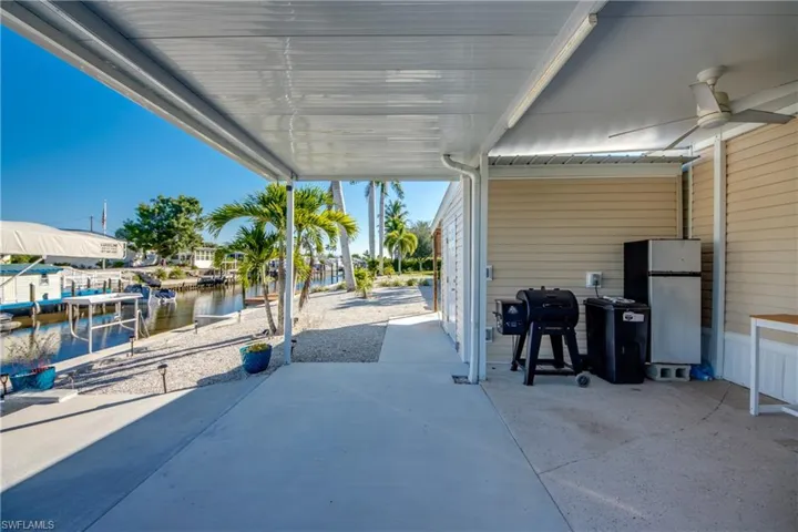 View of patio / terrace featuring a water view, grilling area, a dock, and a ceiling fan